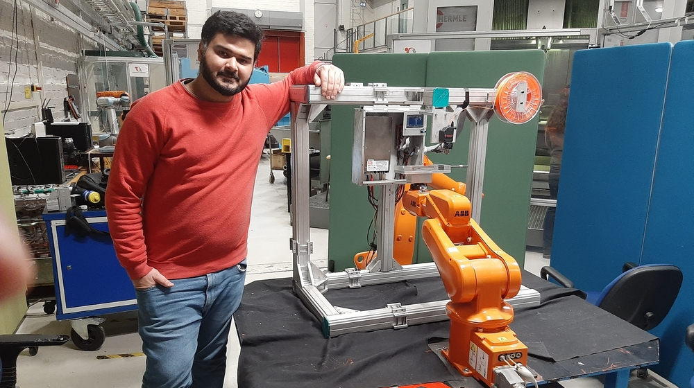 Fahad Ahmad Khan in front of the robot arm.
